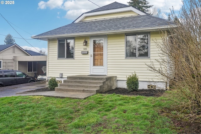 bungalow with roof with shingles and a front lawn