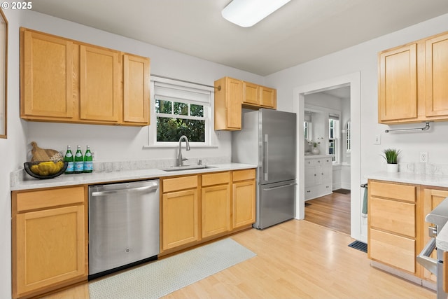 kitchen featuring light wood-style floors, appliances with stainless steel finishes, light brown cabinets, and a sink
