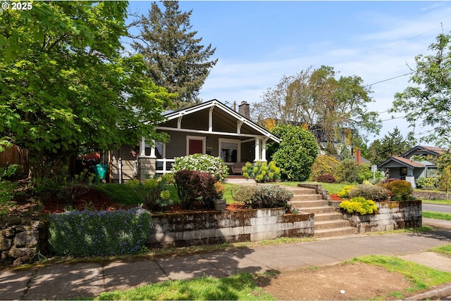 view of front of house featuring a porch, a chimney, and stairs