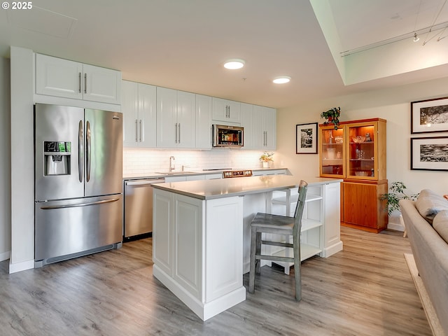 12600 SW Crescent St Unit 213, Beaverton, OR 97005 - kitchen with stainless steel appliances, light wood-style floors, white cabinets, tasteful backsplash, and recessed lighting