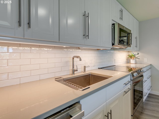 12600 SW Crescent St Unit 213, Beaverton, OR 97005 - kitchen with stainless steel appliances, decorative backsplash, a sink, and light countertops