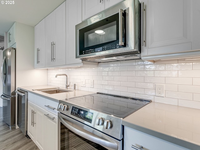 12600 SW Crescent St Unit 213, Beaverton, OR 97005 - kitchen with stainless steel appliances, a sink, white cabinets, and light countertops