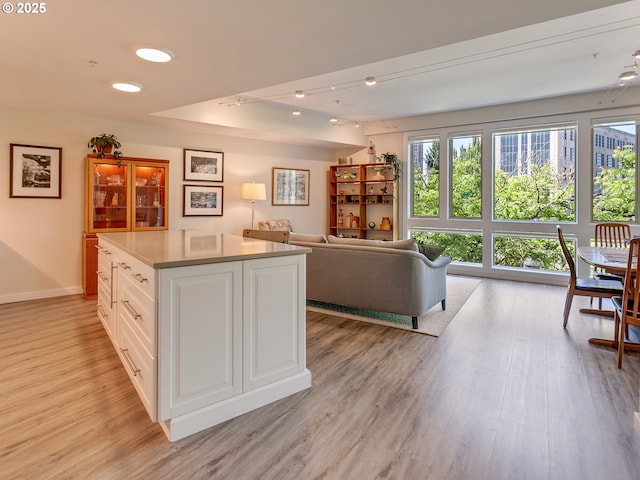 12600 SW Crescent St Unit 213, Beaverton, OR 97005 - kitchen featuring light wood-style flooring, white cabinets, light countertops, open floor plan, and a center island