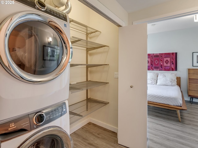 12600 SW Crescent St Unit 213, Beaverton, OR 97005 - washroom featuring stacked washer and clothes dryer, wood finished floors, and baseboards