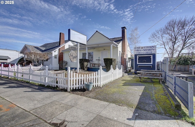 view of home's exterior featuring a fenced front yard, covered porch, and a chimney