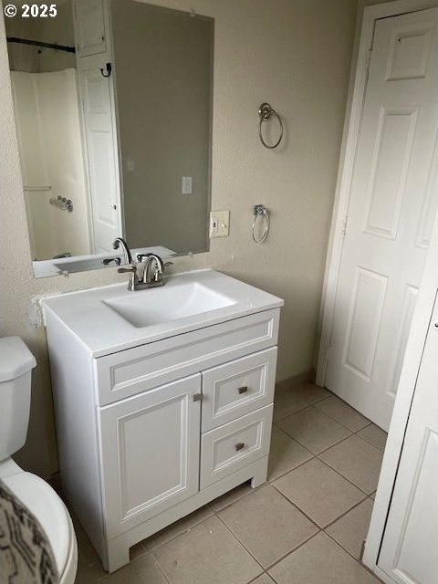 bathroom with toilet, vanity, and tile patterned flooring