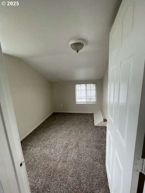 carpeted empty room with lofted ceiling and baseboards