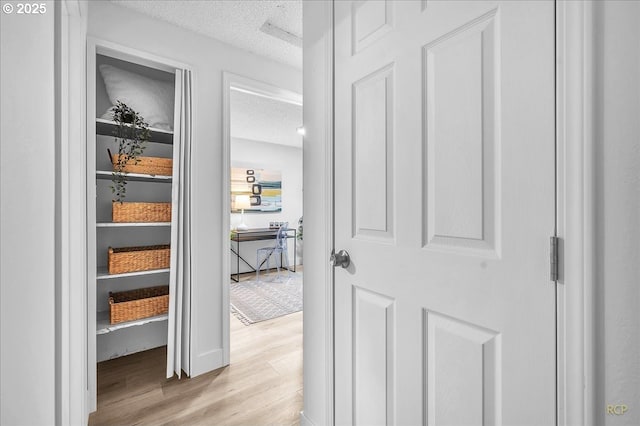 hall featuring a textured ceiling and light hardwood / wood-style floors