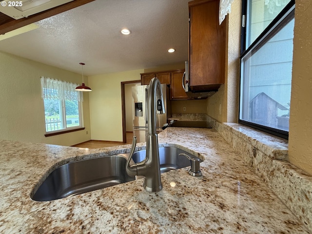 550 Velopa Ct, Brookings, OR 97415 - kitchen with a sink, a textured ceiling, hanging light fixtures, stainless steel fridge, and brown cabinets