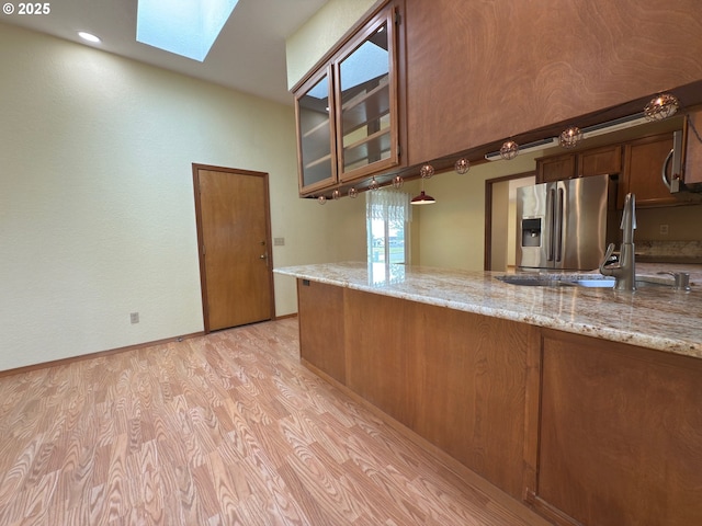 550 Velopa Ct, Brookings, OR 97415 - kitchen with a skylight, stainless steel fridge with ice dispenser, light wood-type flooring, light stone counters, and a sink