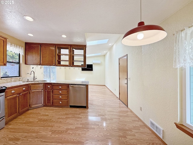 550 Velopa Ct, Brookings, OR 97415 - kitchen with a textured wall, light wood finished floors, a skylight, a sink, and brown cabinetry