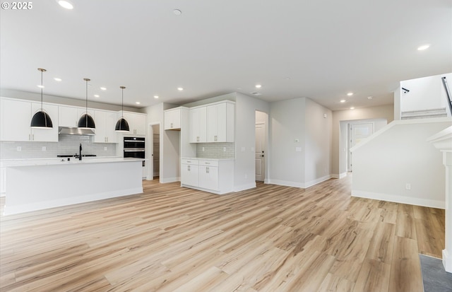 8728 S 4th Way, Ridgefield, WA 98642 - unfurnished living room with light wood finished floors, recessed lighting, a sink, baseboards, and stairs