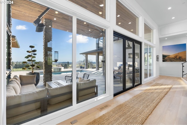 doorway with a wall of windows, visible vents, wood finished floors, and recessed lighting