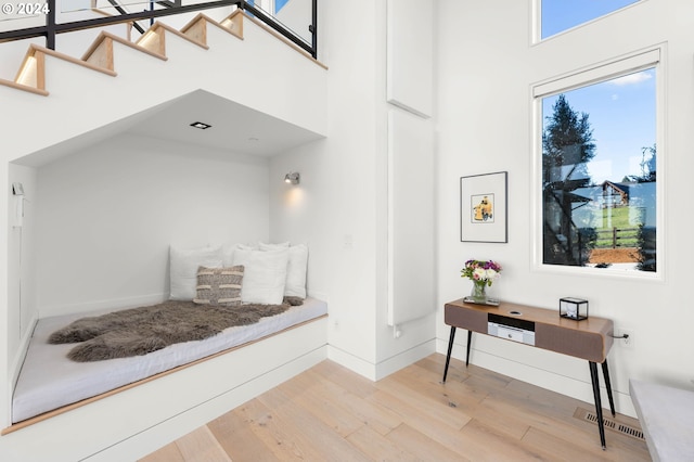 mudroom featuring visible vents, baseboards, light wood-style flooring, and a towering ceiling