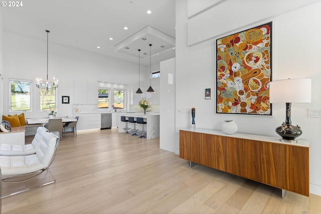 interior space with a high ceiling, a notable chandelier, light wood-style floors, and recessed lighting