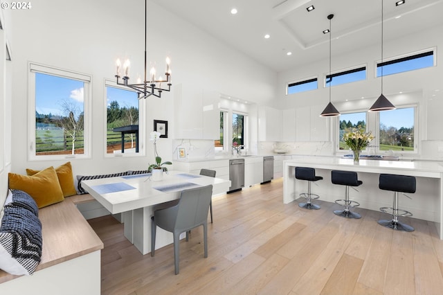 dining room with breakfast area, a towering ceiling, recessed lighting, and light wood finished floors