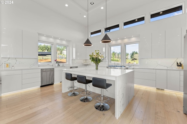 kitchen with a kitchen bar, modern cabinets, white cabinets, light wood finished floors, and dishwasher