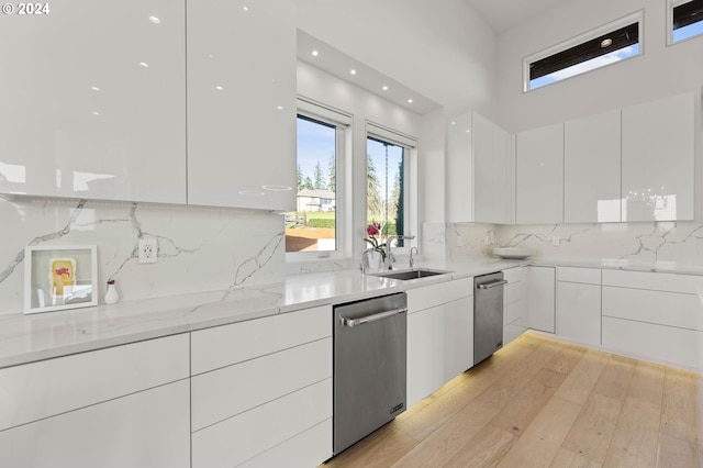 kitchen featuring a sink, light wood-style floors, white cabinetry, modern cabinets, and stainless steel dishwasher