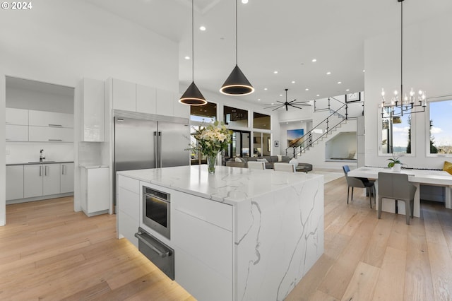 kitchen featuring light wood-type flooring, white cabinets, modern cabinets, a warming drawer, and a sink