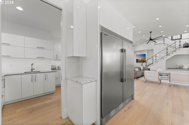 kitchen featuring a sink, modern cabinets, stainless steel built in refrigerator, and white cabinets