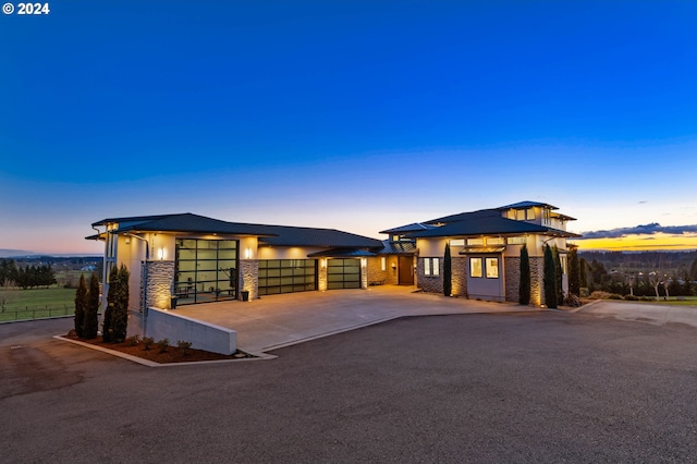 prairie-style home with fence, concrete driveway, stucco siding, a garage, and stone siding