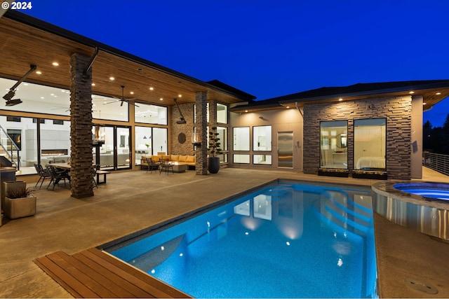 pool at twilight featuring outdoor lounge area, a patio area, and a pool with connected hot tub