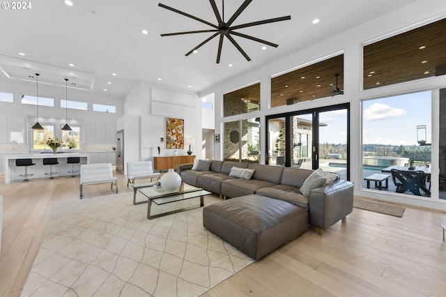 living room featuring recessed lighting, a high ceiling, and light wood-style flooring