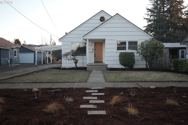 bungalow-style house featuring an outbuilding, a garage, a front yard, and a carport