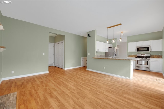 5966 Frost Ln, Lake Oswego, OR 97035 - kitchen featuring stainless steel appliances, light wood finished floors, white cabinets, a peninsula, and pendant lighting