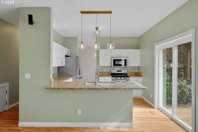5966 Frost Ln, Lake Oswego, OR 97035 - kitchen featuring appliances with stainless steel finishes, light wood-style flooring, light stone counters, a peninsula, and white cabinets