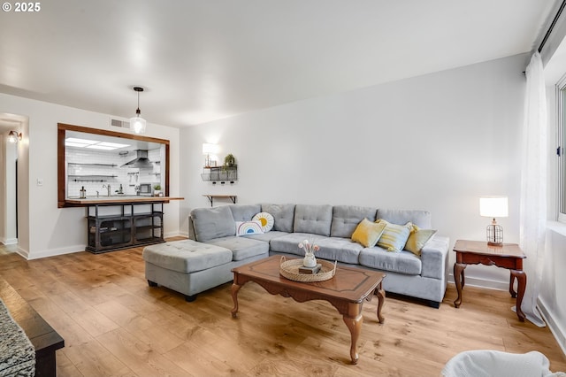 living area featuring baseboards, visible vents, and light wood-style flooring