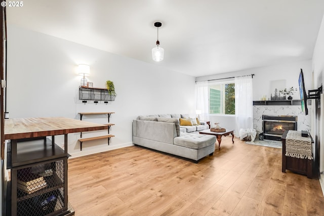 living room with light wood-style floors, baseboards, and a high end fireplace
