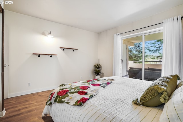 bedroom with wood finished floors, baseboards, and access to outside