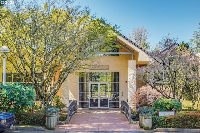 property entrance featuring stucco siding and french doors