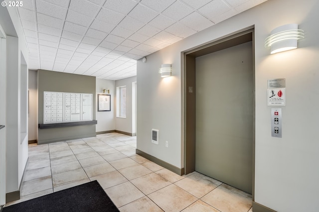 hallway featuring elevator, mail area, and light tile patterned floors