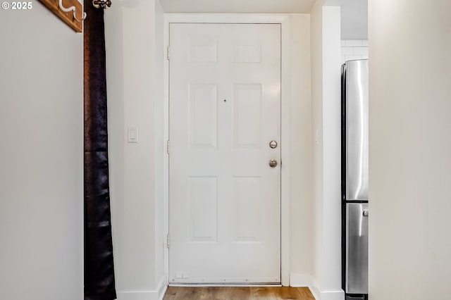 doorway with baseboards and light wood finished floors