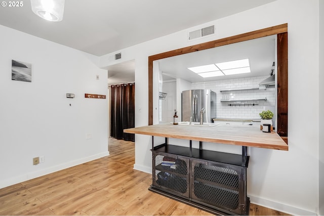 6645 W Burnside St Unit 515, Portland, OR 97210 - kitchen with wood counters, freestanding refrigerator, open shelves, light wood-style floors, and baseboards