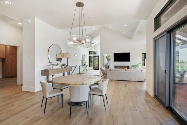 dining space with high vaulted ceiling and light hardwood / wood-style floors