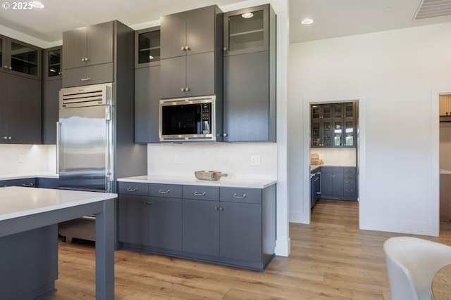 kitchen featuring built in appliances and light hardwood / wood-style flooring