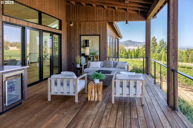 sunroom / solarium with a mountain view, lofted ceiling with beams, french doors, and wine cooler