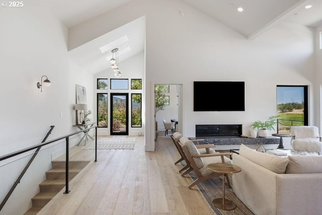 living room with light wood-type flooring, high vaulted ceiling, and french doors