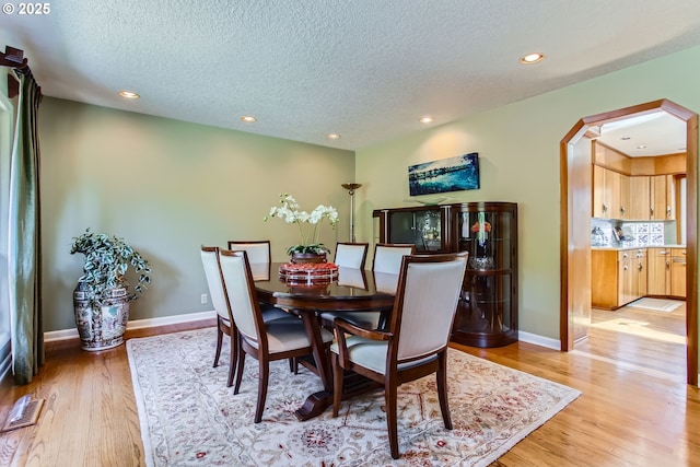 7145 SW Gable Pkwy, Portland, OR 97225 - dining space featuring a textured ceiling, arched walkways, light wood-style floors, and recessed lighting