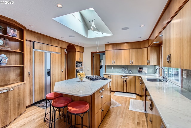 7145 SW Gable Pkwy, Portland, OR 97225 - kitchen featuring a skylight, light wood-style flooring, a kitchen island, paneled built in fridge, and stainless steel gas cooktop