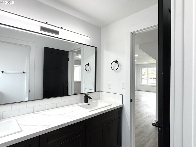 full bath featuring double vanity, wood finished floors, and a sink
