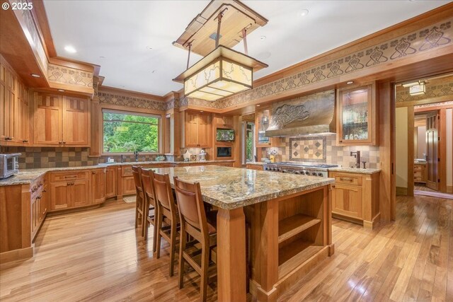 13150 SW Iron Mountain Blvd, Portland, OR 97219 - kitchen featuring open shelves, a center island, crown molding, backsplash, and light stone countertops