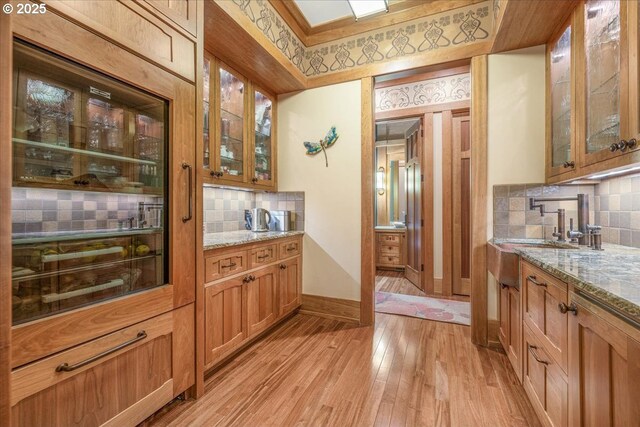 13150 SW Iron Mountain Blvd, Portland, OR 97219 - bar area featuring decorative backsplash, light wood finished floors, a sink, and baseboards
