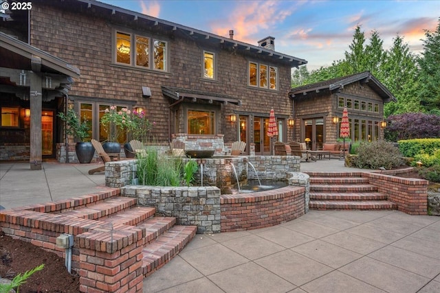 13150 SW Iron Mountain Blvd, Portland, OR 97219 - back of house at dusk with a patio and a chimney