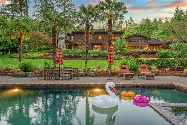 13150 SW Iron Mountain Blvd, Portland, OR 97219 - pool at dusk featuring a patio area, an outdoor pool, a yard, and outdoor dining space