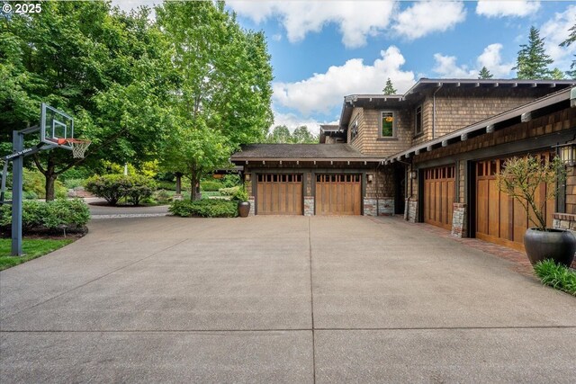 13150 SW Iron Mountain Blvd, Portland, OR 97219 - view of home's exterior with concrete driveway, stone siding, and an attached garage