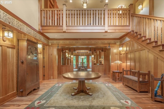13150 SW Iron Mountain Blvd, Portland, OR 97219 - entryway with french doors, light wood-style floors, a high ceiling, wooden walls, and stairs